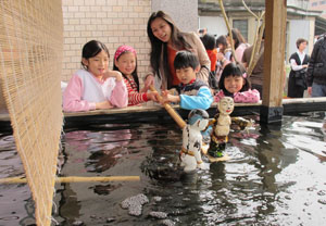 A teacher and her students try coordinating two Vietnamese water puppets